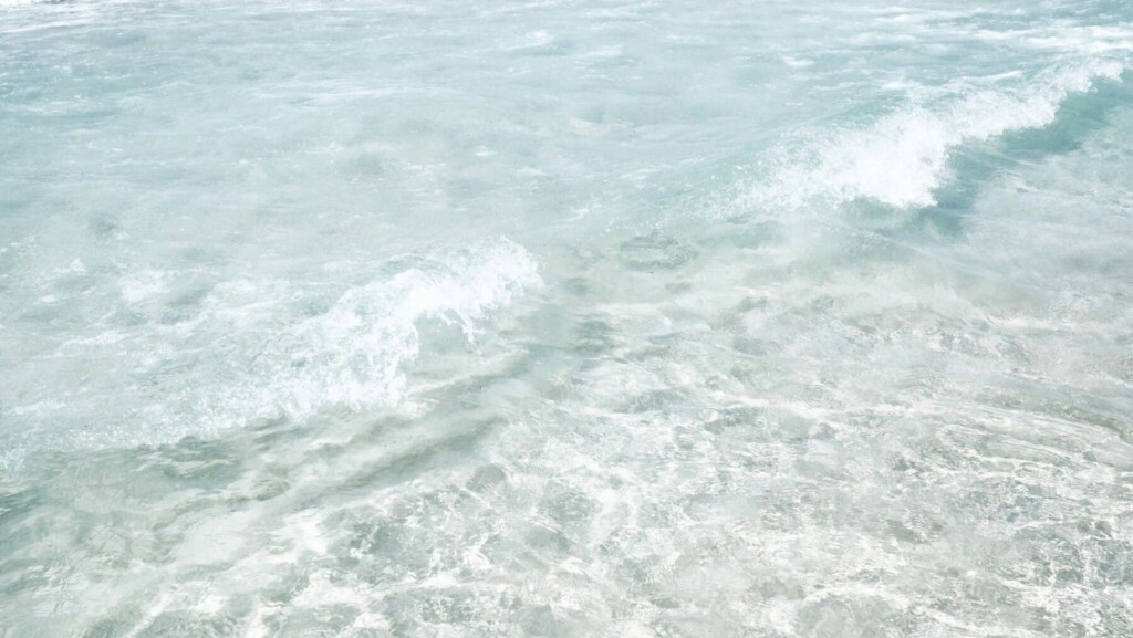 Clear shallow ocean water with gentle waves, used to illustrate Siesta Key water clarity planning tips (Siesta Key water clarity)