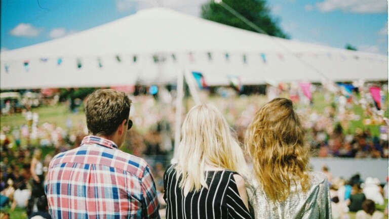 Three people watching a Sarasota festival crowd in Sarasota, Florida, showing the live events vibe featured in this Siesta Key and Sarasota events by season guide