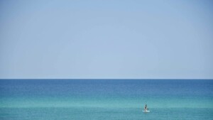 Paddleboarder on calm turquoise Gulf water near Siesta Key, Florida, showing swimming conditions for a Siesta Key water temperature by month guide